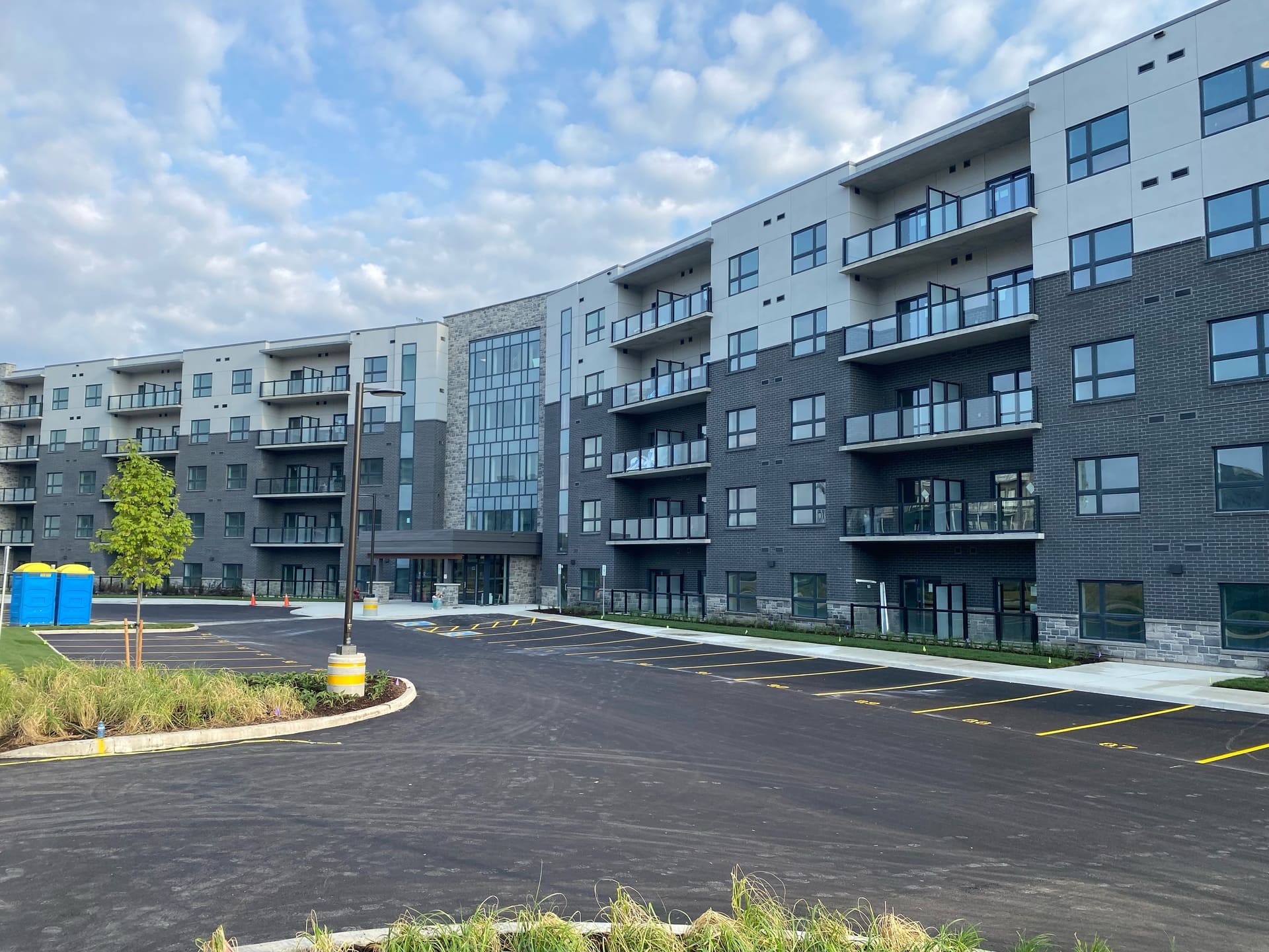 Newly paved parking lot in front of a modern apartment building in Kitchener, showcasing durable driveway paving by 5 Star Paving.